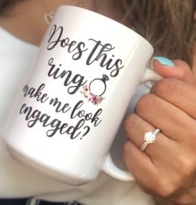 mug with writing on it and engagement ring