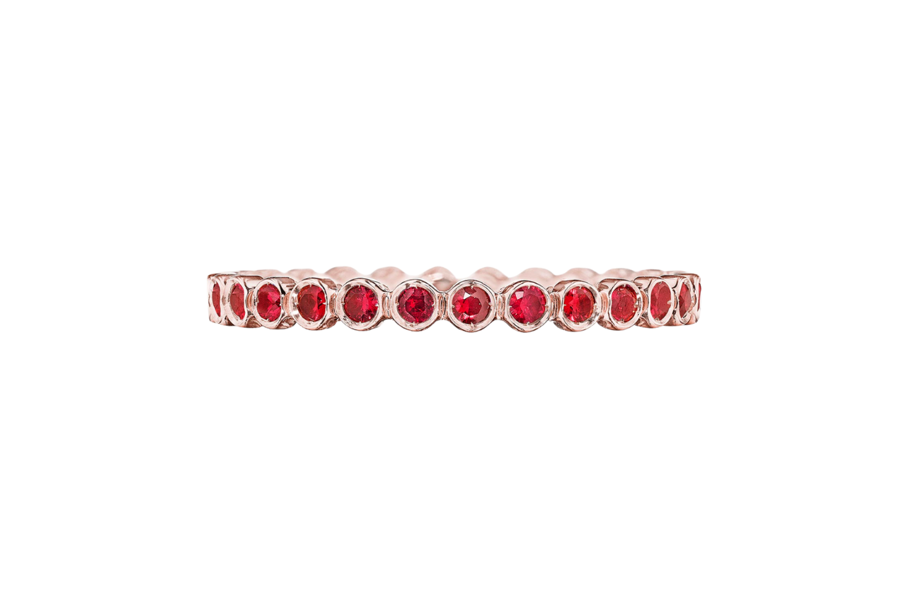 A close-up of the TACORI rose gold round bezel droplet wedding band with rubies.