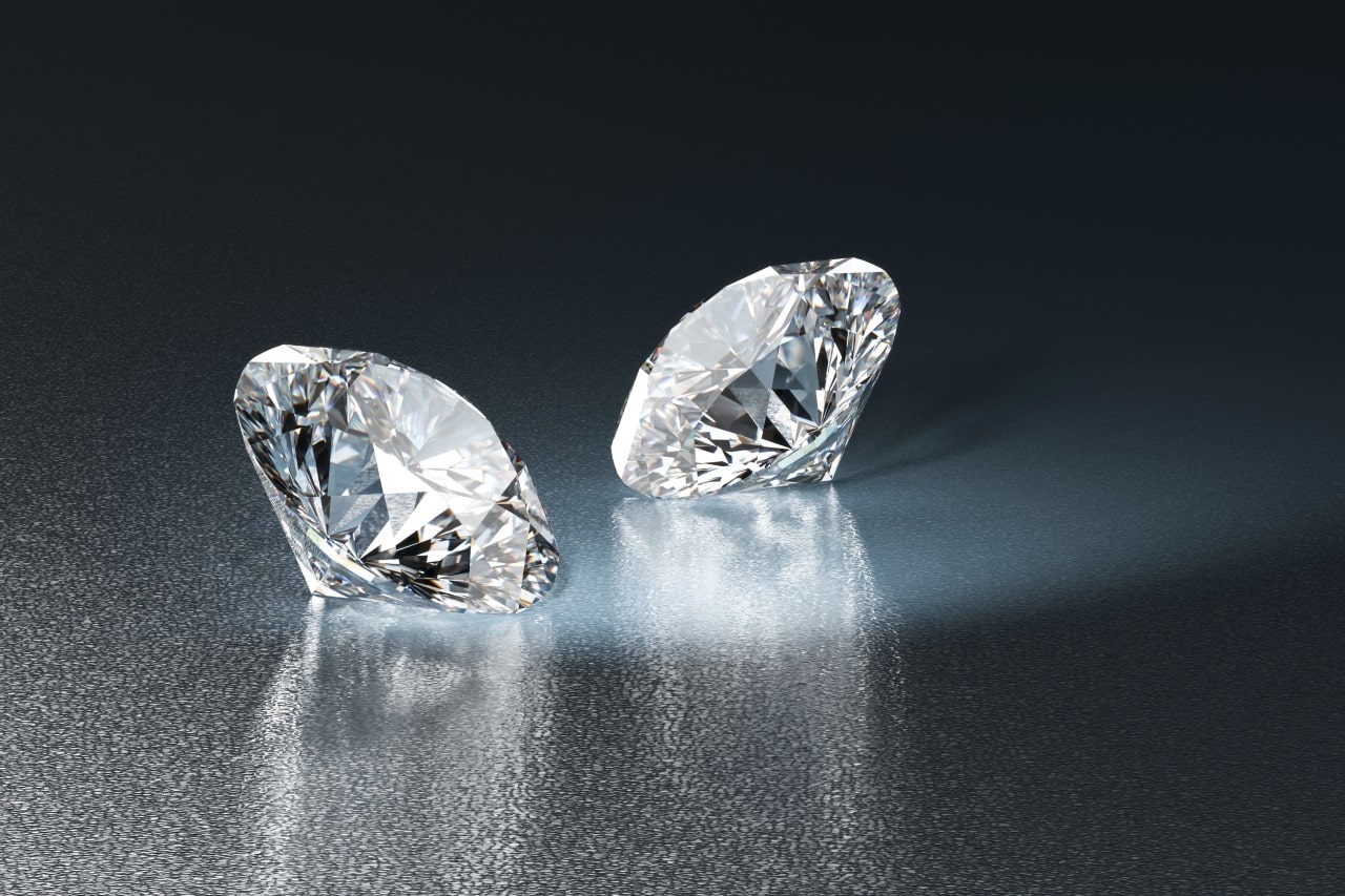 Two loose diamonds on a reflective dark surface