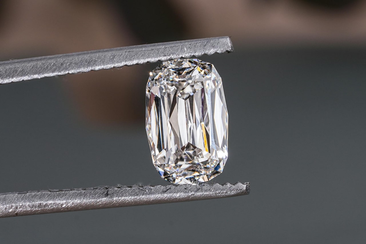 A radiant cut diamond held by tweezers