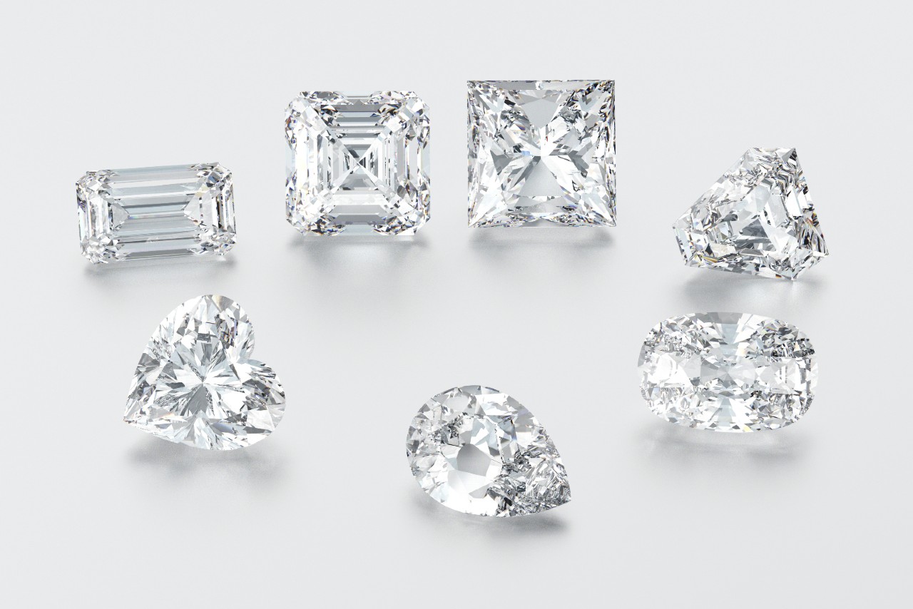 Several diamonds of different cuts – emerald, cushion, princess, oval, pear, and heart – on a white surface