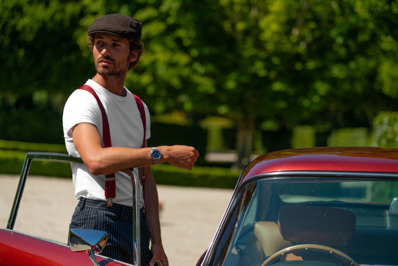 A man resting his arm on a vintage open car door, showcasing his luxury watch.