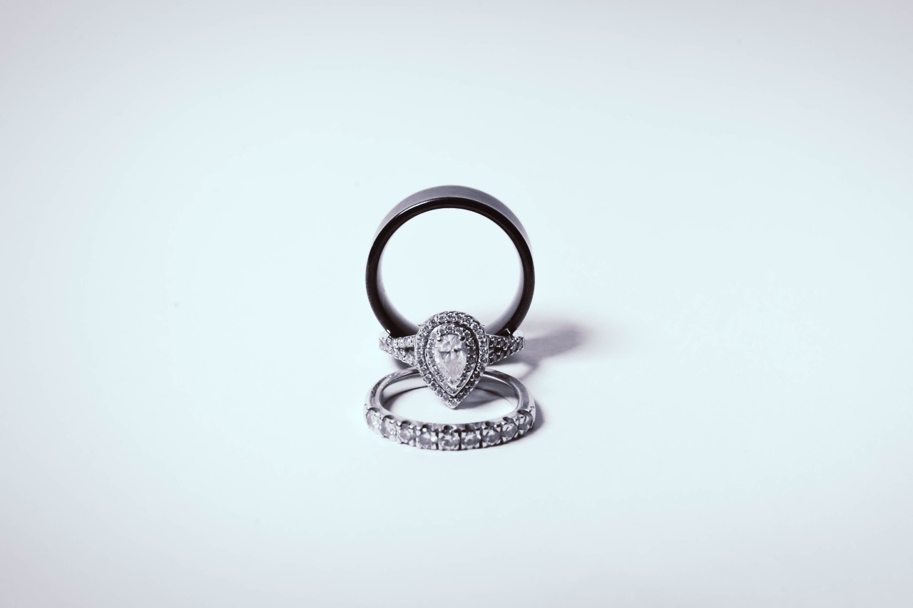 Engagement ring with pear shaped diamond set between two wedding bands.