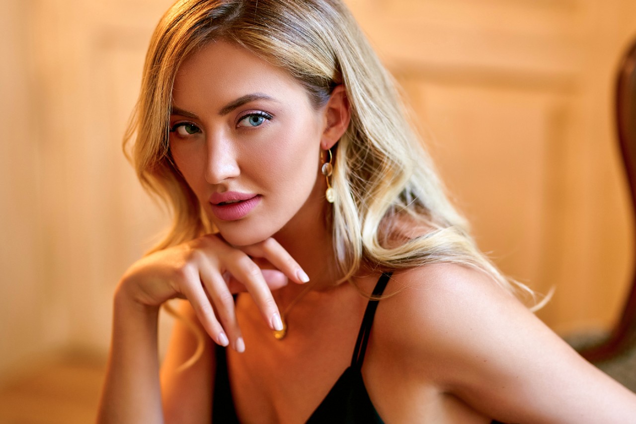 A blond woman gazing at the side, showcasing a yellow gold drop earrings