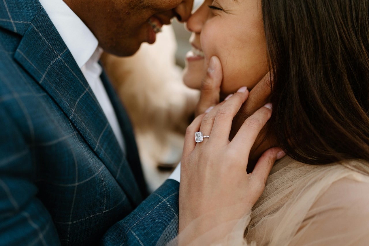 A close-up of a bride and groom embracing, with emphasis on the bride’s stunning engagement ring. A close-up of a bride and groom embracing, with emphasis on the bride’s stunning engagement ring.