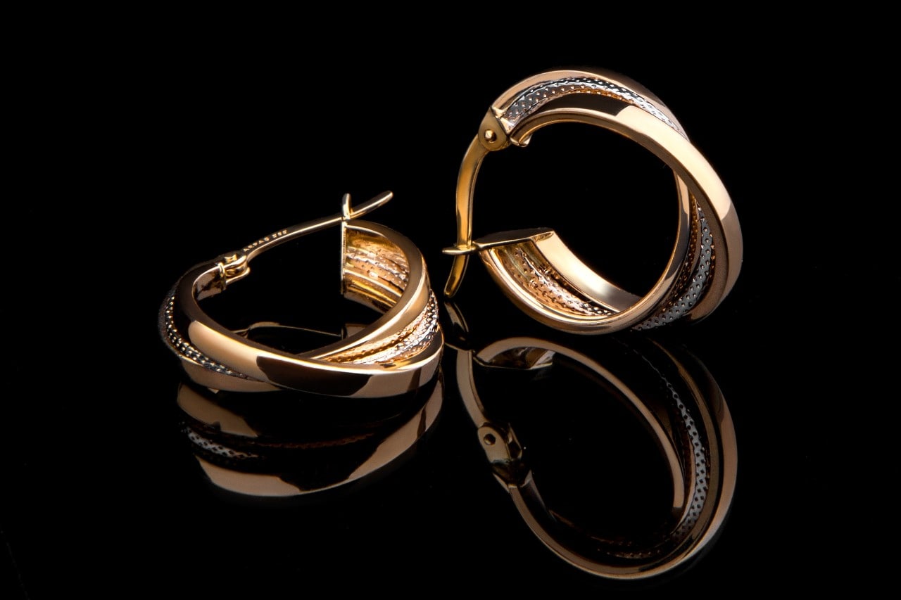 Yellow gold hoop diamond earrings on a black reflective surface