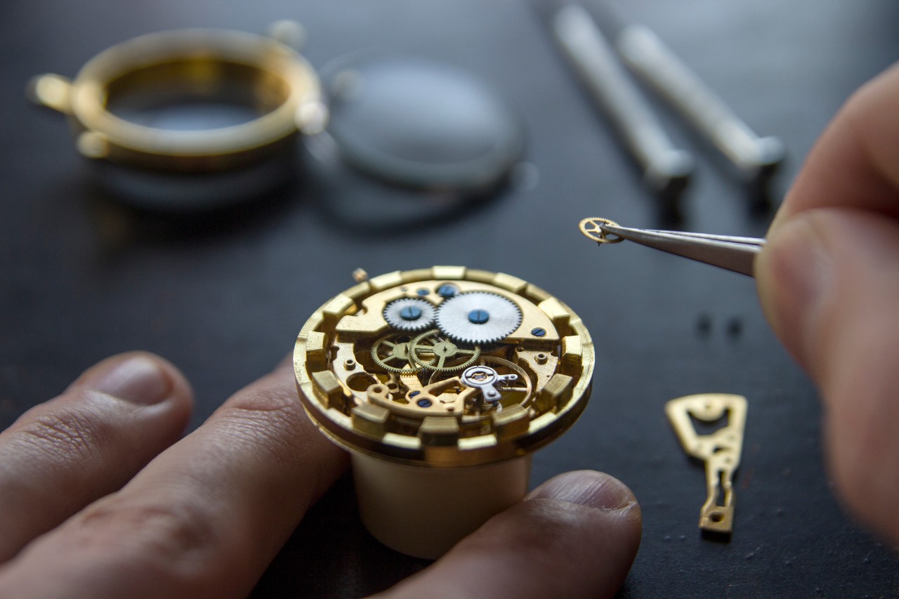 A watchmaker carefully installs a tiny gear into a mechanical watch movement using precision tweezers. A watchmaker carefully installs a tiny gear into a mechanical watch movement using precision tweezers.
