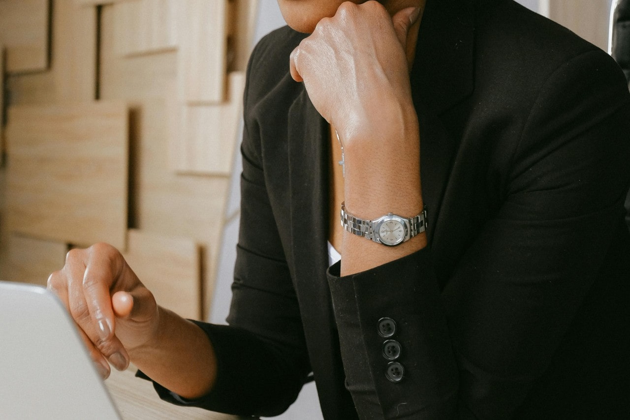 A close-up of a well-dressed woman wearing a dress watch as she works on a laptop. A close-up of a well-dressed woman wearing a dress watch as she works on a laptop.